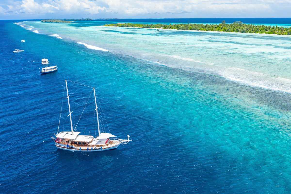 A liveaboard sailing yacht moored off an atoll in the Maldives, ready for diving