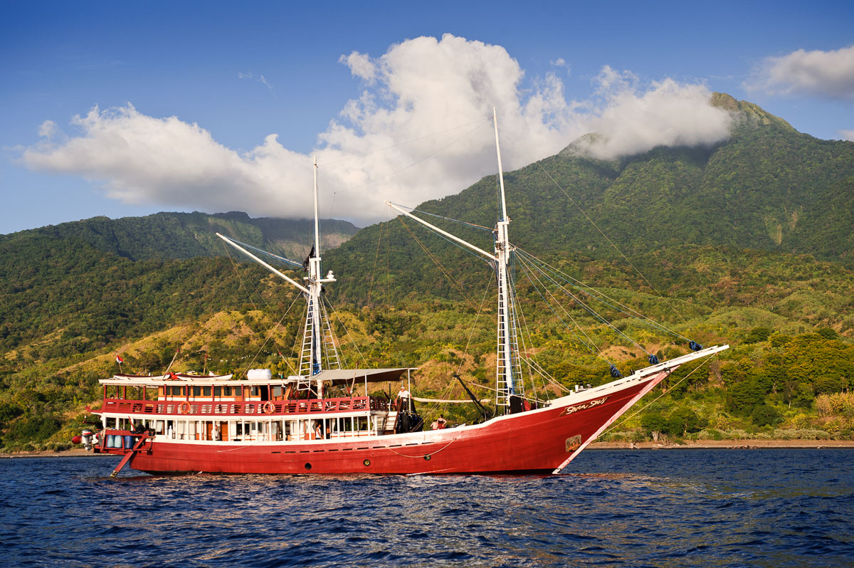 A phinisi liveaboard sailing past the island of Sangeang, near Komodo, Indonesia